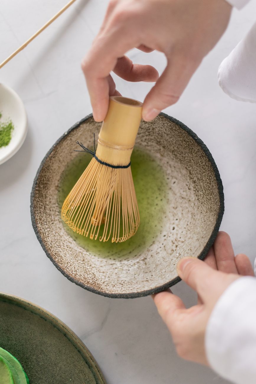 Traditional Japanese tea master whisking matcha in ceramic bowl